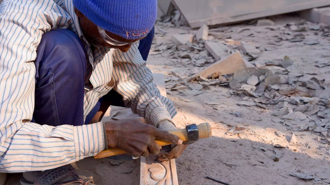 Stone artisan using a hammer and chisel, Uvesh Sandstone Works.